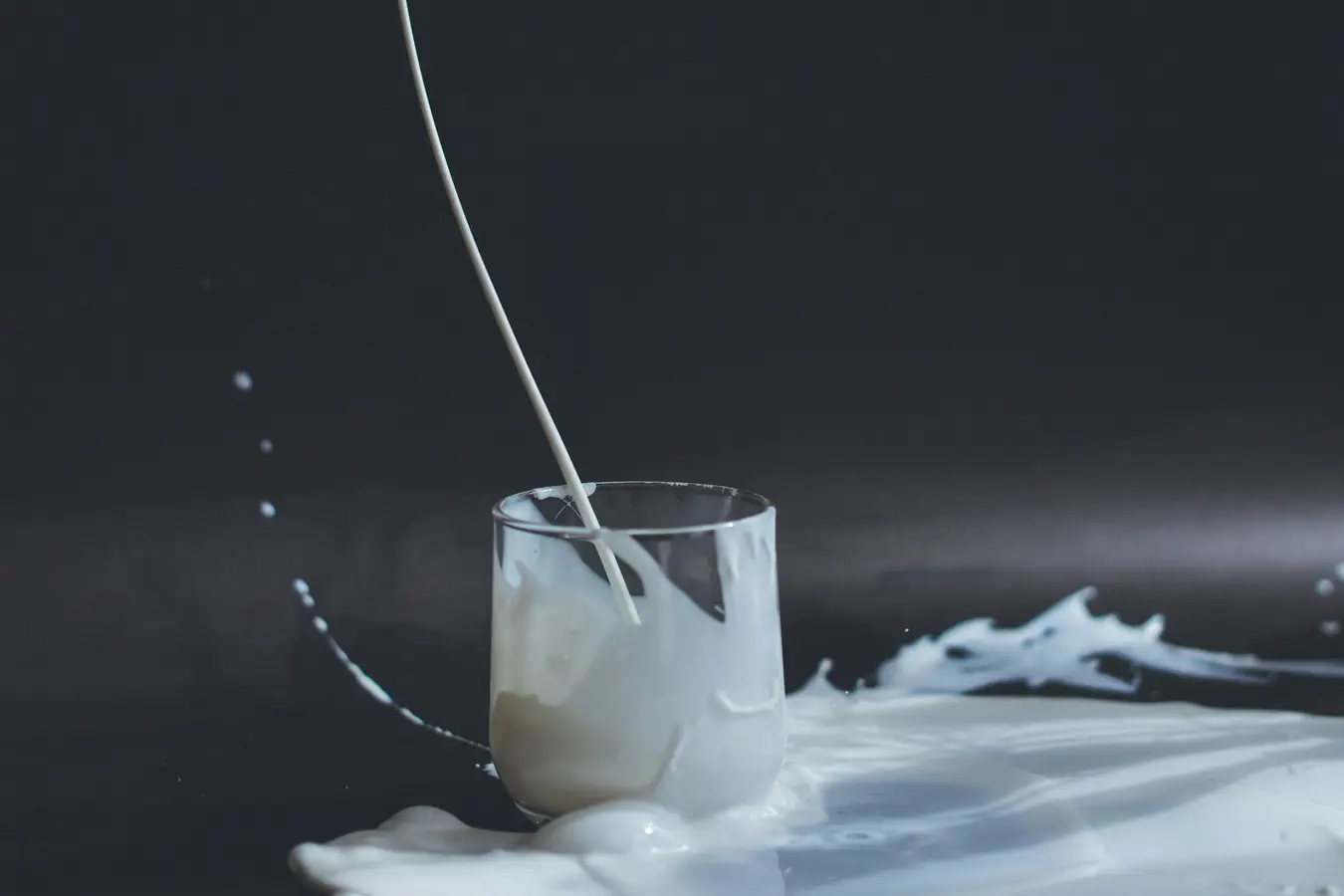 Oatly Aktie Prognose 2025. Ein Glas mit verschütteter pflanzlicher Milch – Symbolbild für die Volatilität der Oatly Aktie